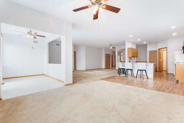 unfurnished living room featuring ceiling fan and light colored carpet