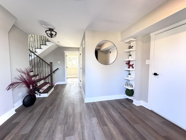 foyer featuring dark wood finished floors, stairs, and baseboards