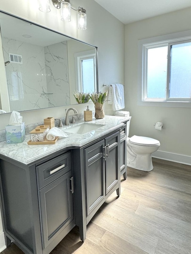 bathroom with visible vents, baseboards, toilet, wood finished floors, and vanity