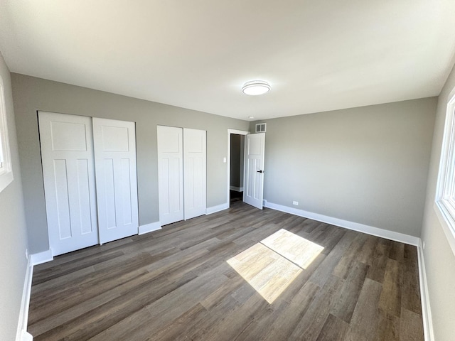 unfurnished bedroom featuring visible vents, two closets, and baseboards