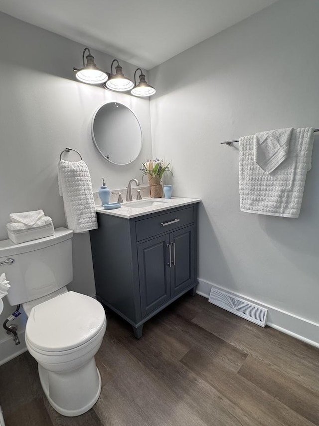 bathroom featuring vanity, wood finished floors, visible vents, baseboards, and toilet