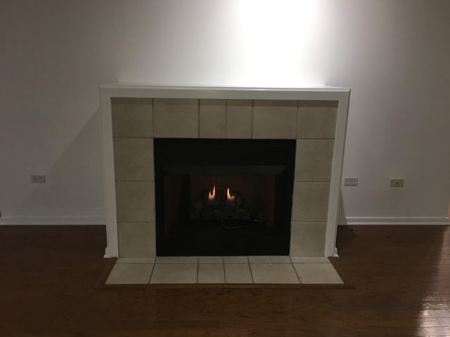 details with hardwood / wood-style flooring and a tile fireplace