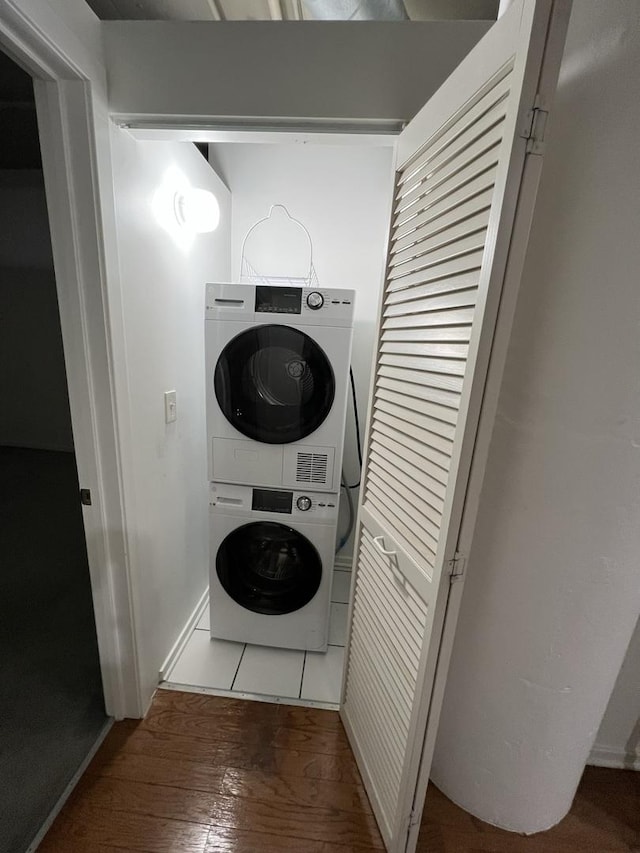 laundry room featuring hardwood / wood-style flooring and stacked washer / dryer