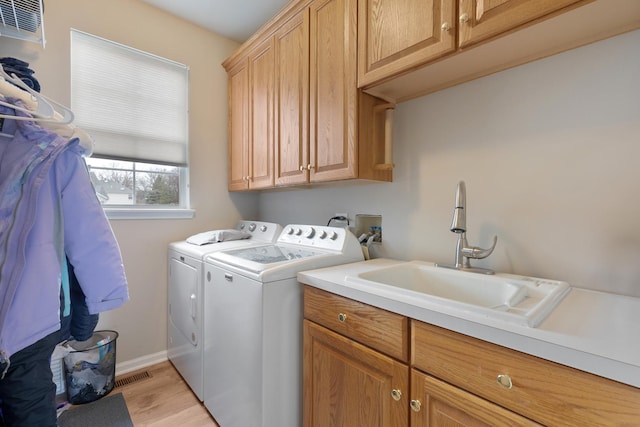 laundry room featuring sink, light hardwood / wood-style flooring, cabinets, and independent washer and dryer