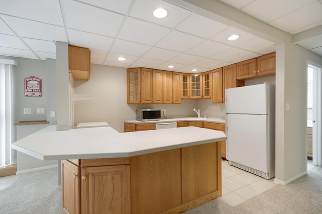 kitchen with light carpet, a drop ceiling, white appliances, and sink