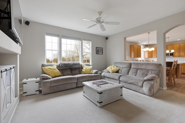 living room with light colored carpet and ceiling fan with notable chandelier