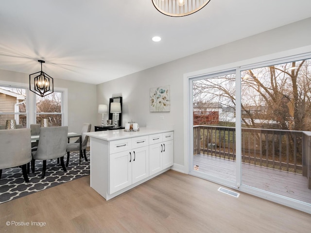 kitchen featuring light hardwood / wood-style flooring, a healthy amount of sunlight, decorative light fixtures, and an inviting chandelier