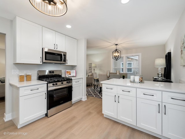 kitchen with white cabinets, decorative light fixtures, and appliances with stainless steel finishes