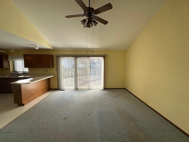 kitchen featuring ceiling fan, sink, lofted ceiling, and light carpet