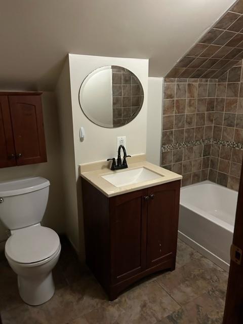 full bathroom with tile patterned floors, vanity, tiled shower / bath combo, and toilet