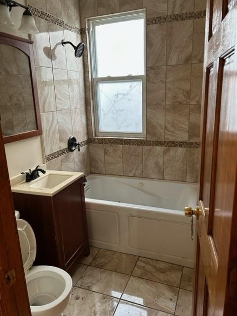 full bathroom featuring tile patterned floors, vanity, toilet, and tiled shower / bath