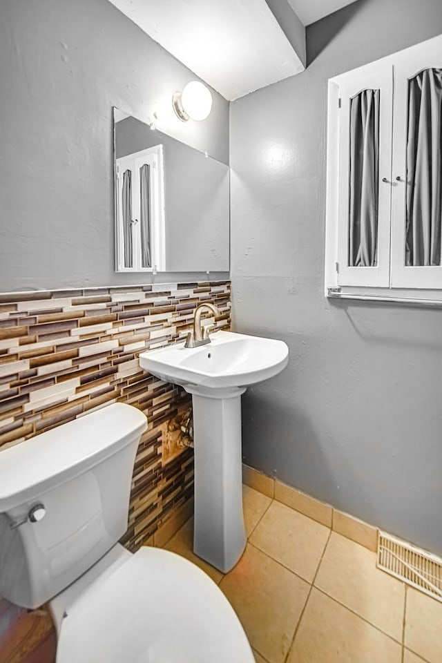 bathroom featuring tile patterned flooring, toilet, and backsplash