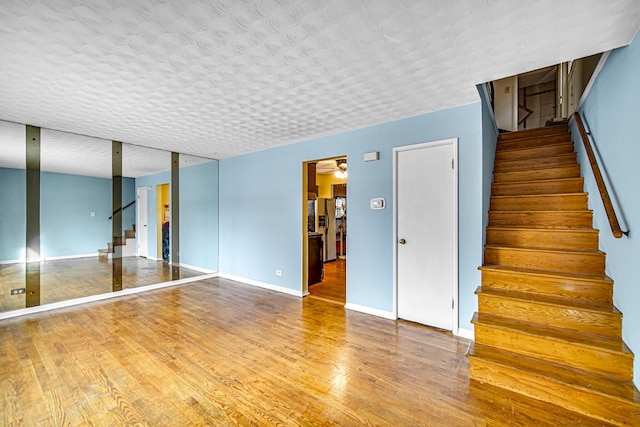 staircase featuring ceiling fan, wood-type flooring, and a textured ceiling