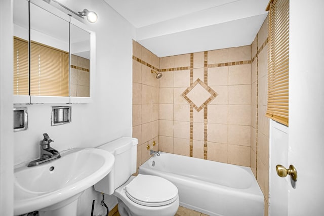 full bathroom featuring sink, tiled shower / bath, and toilet