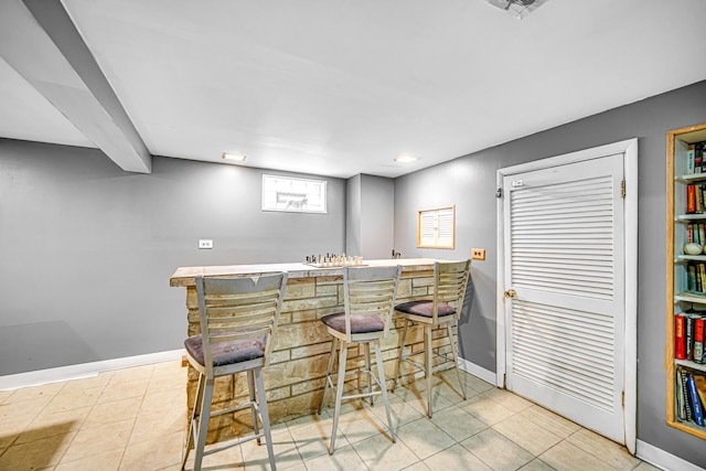 kitchen featuring a breakfast bar, light tile patterned floors, and kitchen peninsula