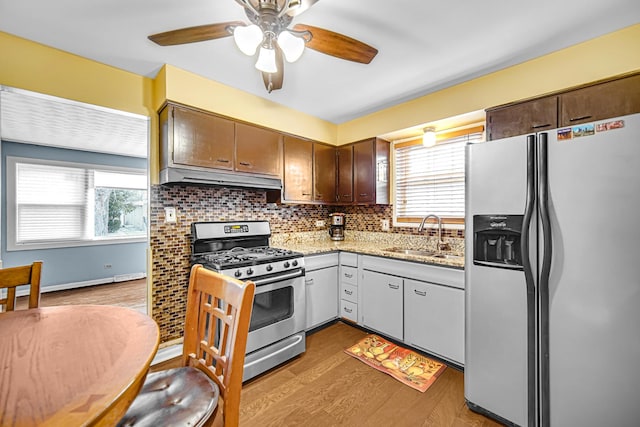 kitchen with backsplash, sink, ceiling fan, light wood-type flooring, and stainless steel appliances