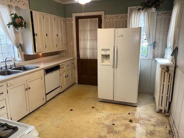 kitchen with white cabinets, white appliances, sink, and radiator