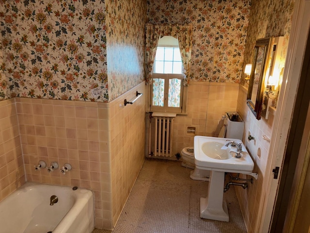 bathroom with tile patterned floors, radiator, tile walls, toilet, and a bathing tub