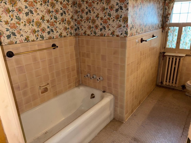 bathroom with radiator heating unit, a bathtub, tile walls, and tile patterned flooring