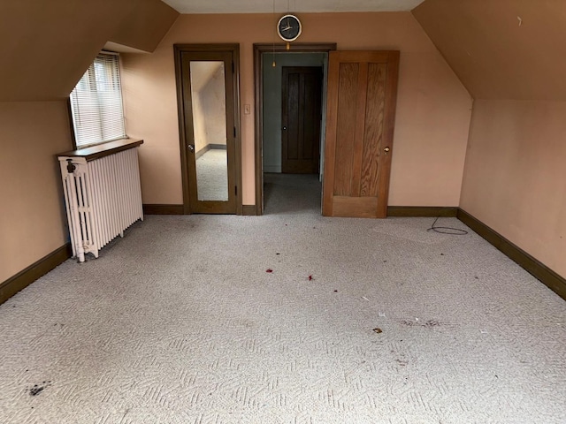 additional living space featuring light colored carpet, lofted ceiling, and radiator