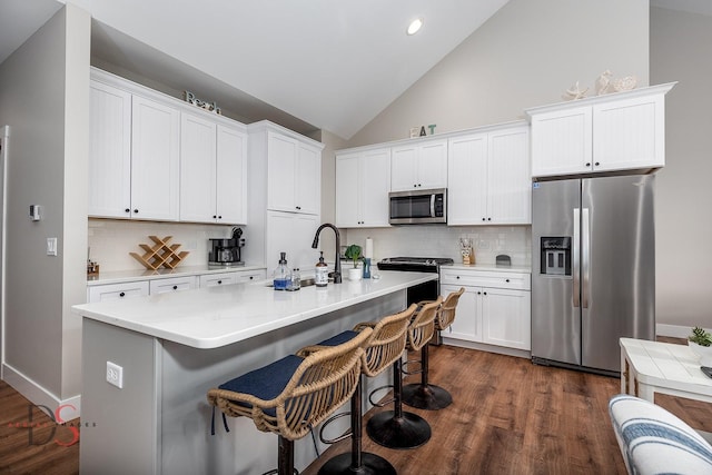 kitchen with decorative backsplash, appliances with stainless steel finishes, white cabinetry, and a kitchen island with sink