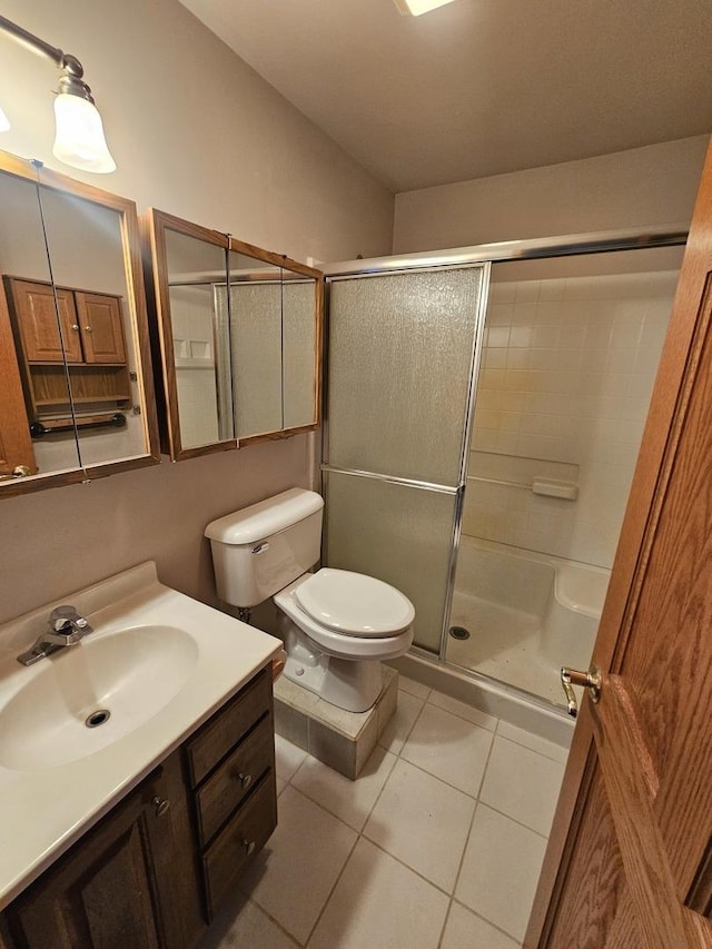 bathroom with toilet, vanity, tile patterned floors, and an enclosed shower