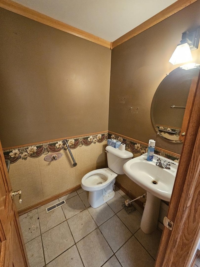 bathroom with toilet, tile patterned floors, ornamental molding, and sink