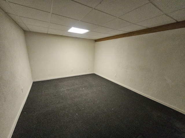 unfurnished room featuring a paneled ceiling and dark carpet