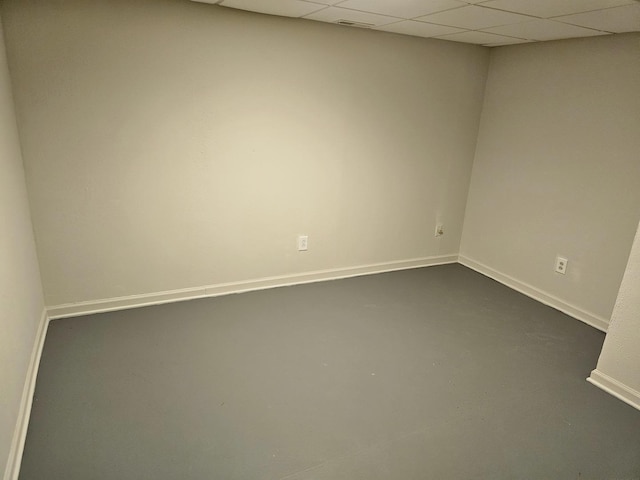 unfurnished room featuring concrete flooring and a drop ceiling