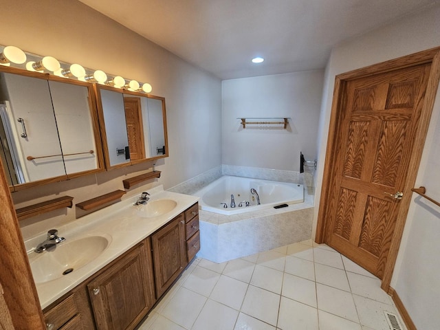 bathroom featuring tile patterned flooring, vanity, and tiled tub