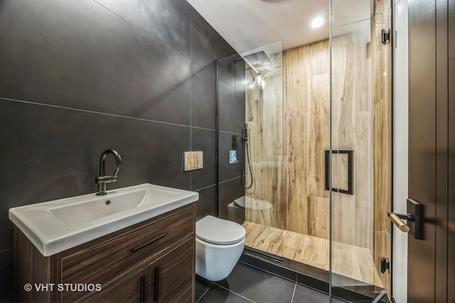 bathroom featuring tile patterned floors, toilet, an enclosed shower, tile walls, and vanity