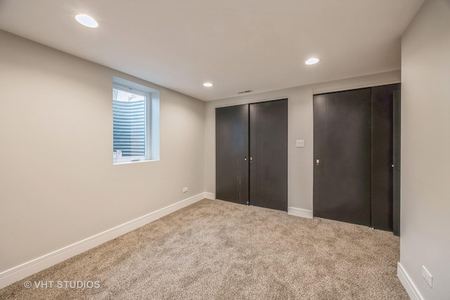 unfurnished bedroom with carpet flooring and two closets