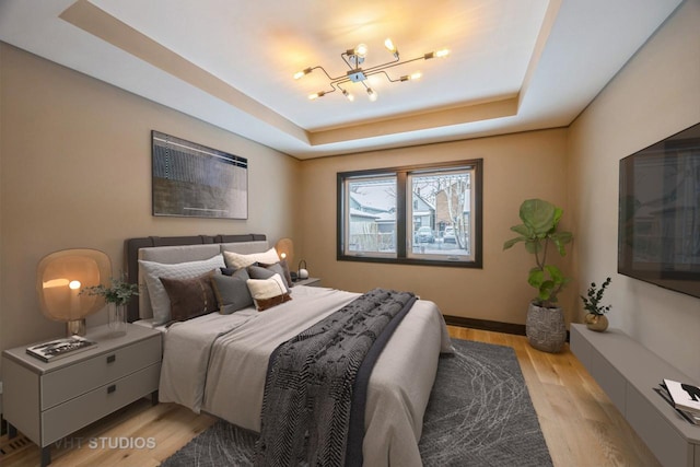 bedroom featuring a tray ceiling and light wood-type flooring