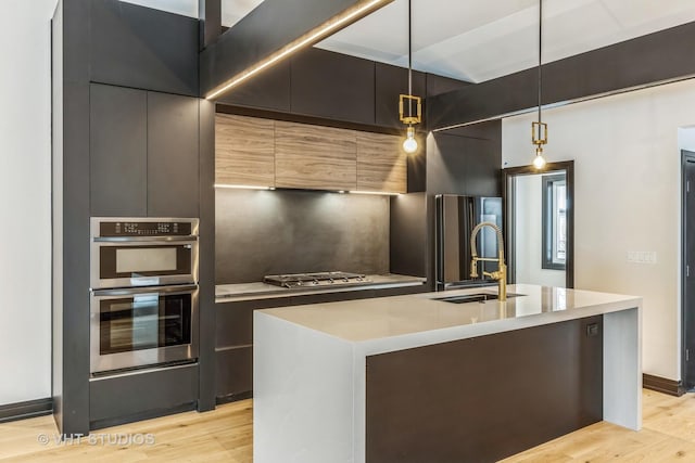 kitchen with sink, hanging light fixtures, and a kitchen island with sink