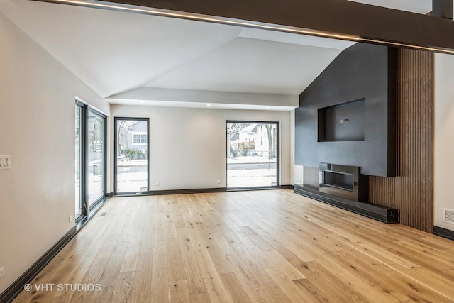 unfurnished living room with a fireplace, vaulted ceiling, and light wood-type flooring