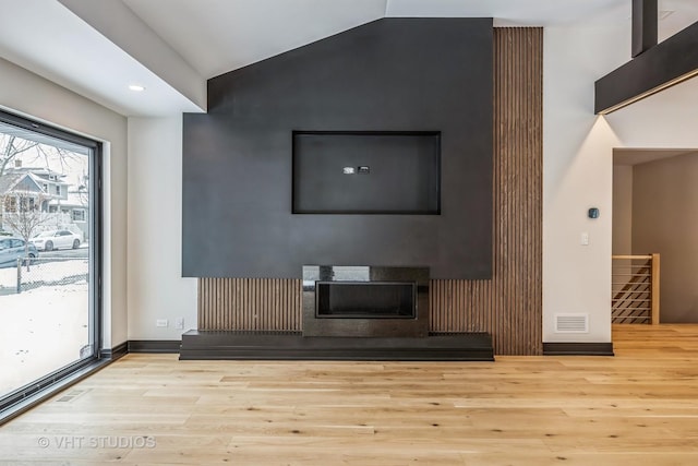 unfurnished living room with vaulted ceiling and light hardwood / wood-style flooring