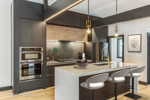 kitchen featuring pendant lighting, sink, a kitchen island with sink, and appliances with stainless steel finishes