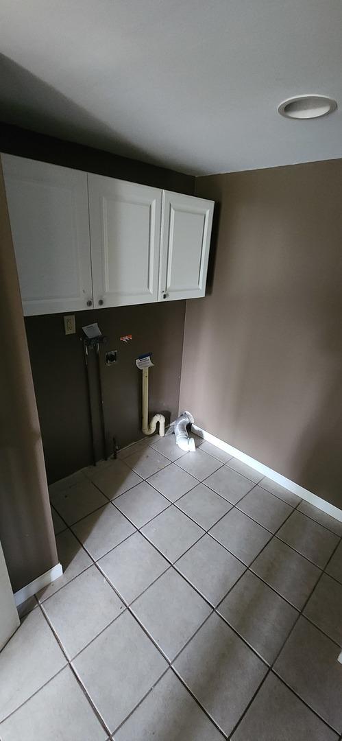 laundry area with cabinets and light tile patterned floors