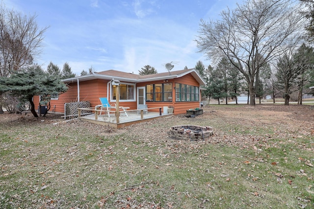 rear view of property with a sunroom, an outdoor fire pit, and a wooden deck