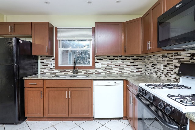 kitchen featuring light stone countertops, sink, tasteful backsplash, light tile patterned floors, and black appliances