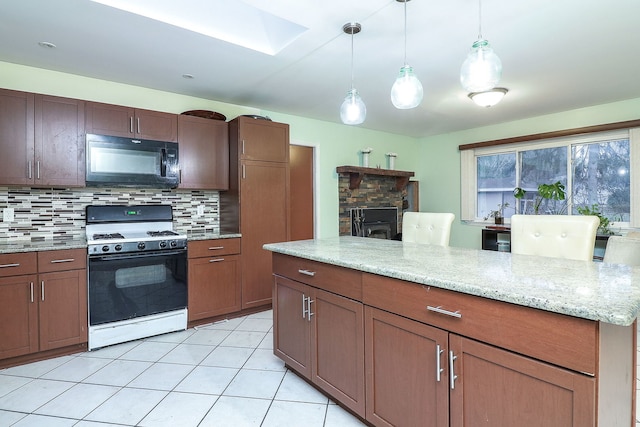 kitchen with gas range, backsplash, decorative light fixtures, and light tile patterned floors