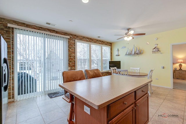 kitchen featuring stainless steel fridge, ceiling fan, a center island, and light tile patterned floors