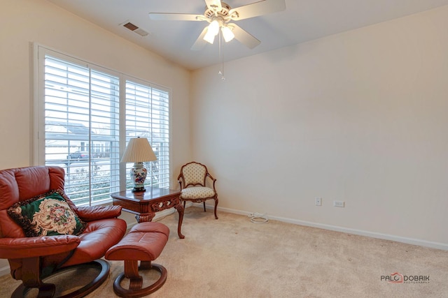 living area featuring light colored carpet and ceiling fan