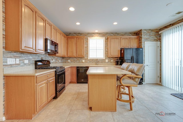 kitchen with black appliances, sink, light tile patterned floors, a kitchen island, and a kitchen bar