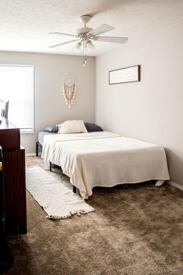 bedroom with dark colored carpet, a textured ceiling, and ceiling fan