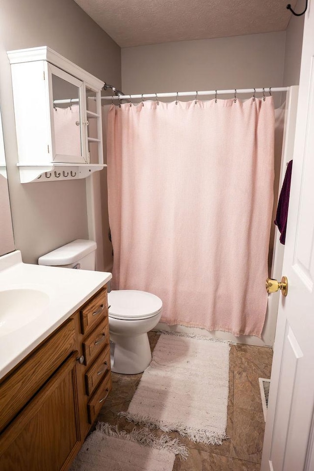 bathroom with vanity, curtained shower, toilet, and a textured ceiling