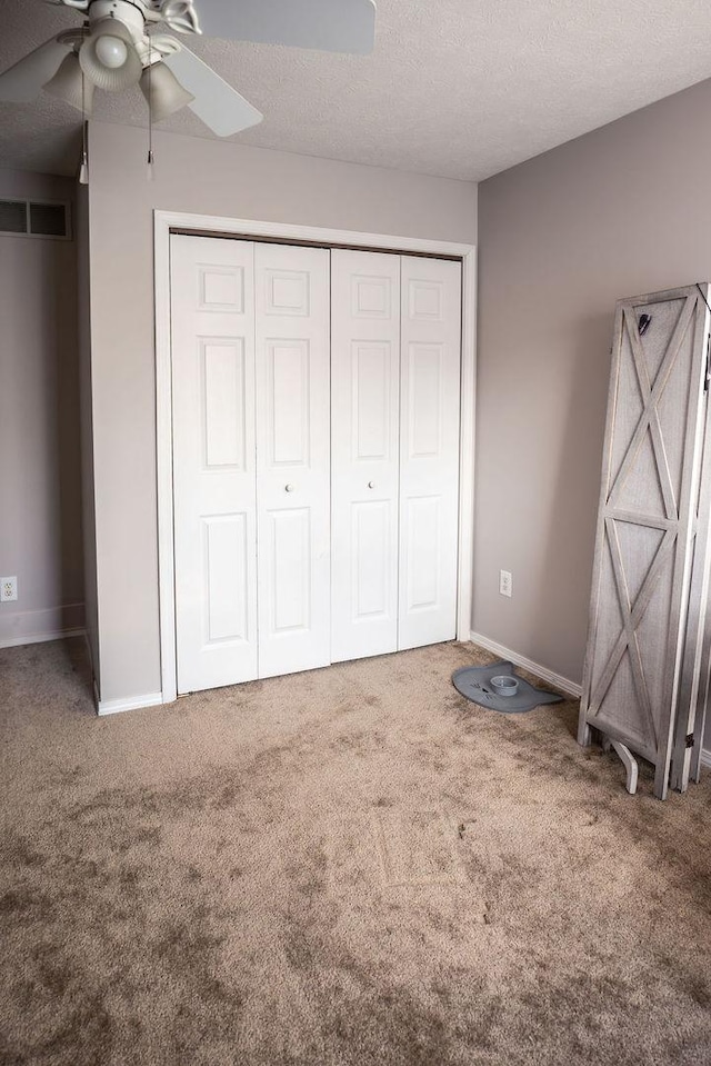 unfurnished bedroom featuring ceiling fan, carpet floors, a textured ceiling, and a closet