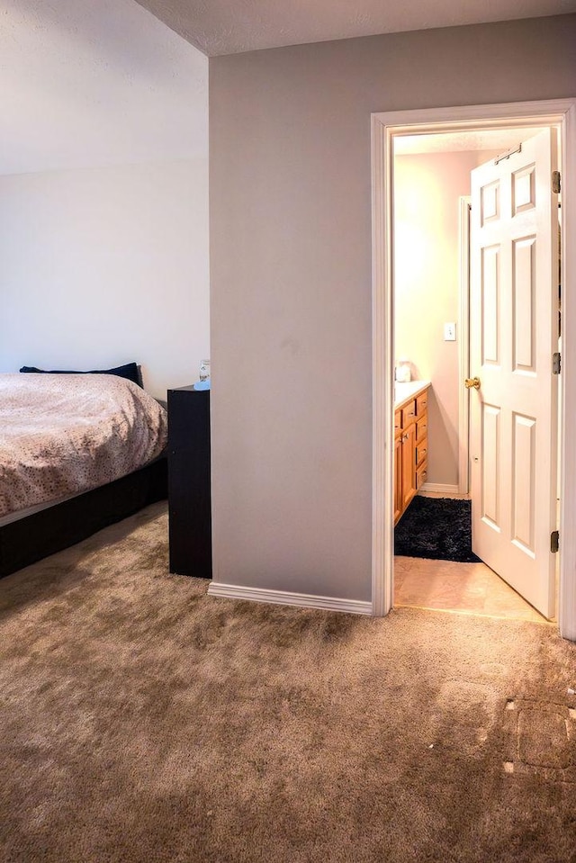 bedroom featuring light carpet and connected bathroom