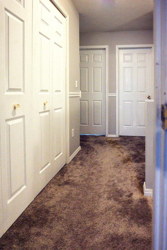 hall with dark colored carpet