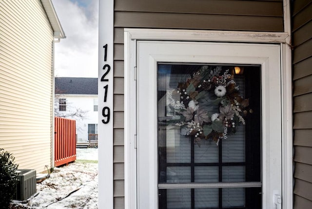 snow covered property entrance with central air condition unit